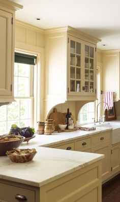 a kitchen filled with lots of counter top space and white cabinets next to a window