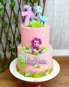 a three tiered cake decorated with animals and plants on top of a wooden table