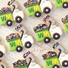 some decorated cookies are on a table with a toy truck in the middle and sprinkles all over them