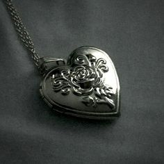 a heart shaped locke on a chain with roses and leaves in the shape of a flower