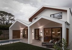 a white house with a pool in the back yard and an outdoor living area next to it