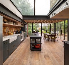 an open kitchen and dining area with wood flooring, glass walls, and skylights