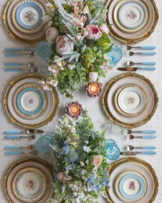 the table is set with plates and flowers