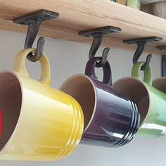 coffee mugs are hanging from hooks on the wall