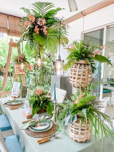 the table is set with plants and place settings