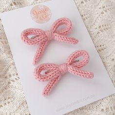 two pink crochet bows on top of a card