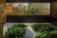 the walkway is lined with plants and rocks, leading to an open area that has a stone wall on one side