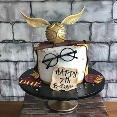 a birthday cake decorated with glasses and a hat on top of a brick wall background