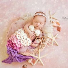 a baby is laying in a basket with seashells