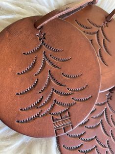 two brown leather coasters sitting on top of a white blanket