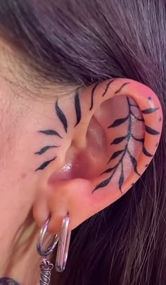 a woman with tattoos on her ear and behind the ear is a pair of hoop earrings