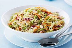 a white bowl filled with coleslaw salad on top of a blue table cloth