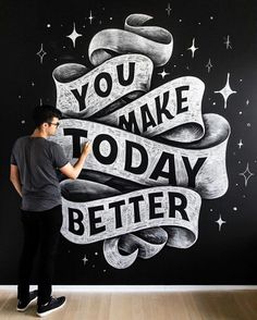 a man standing in front of a black and white wall that says, you make today better