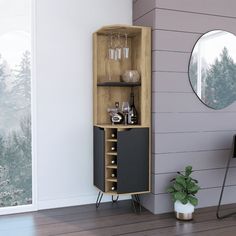 a wooden cabinet with wine glasses on it next to a mirror and potted plant