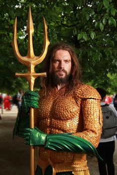 a man dressed in gold and green holding a golden spear