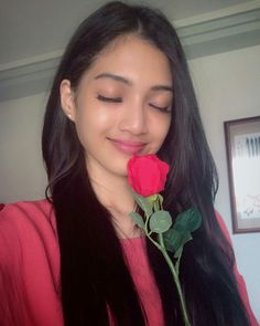 a woman with long black hair holding a red rose