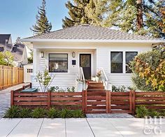 a white house with wooden fence and trees in the background