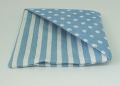 a blue and white polka dot cloth folded on top of each other with a black cat sitting next to it