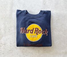 "Hard Rock London sweatshirt in good vintage condition. Size tag marked size L but would fit modern day women's size medium best. Please refer to all photos for wear, specifically last photo for small hole. Length: 24.5\", shoulder to hem Width: 21\", pit to pit (Measured flat) A note on sweatshirt sizing: To ensure a perfect fit, we recommend measuring your favorite sweatshirt and comparing it to the measurements specified above for this item. PLEASE READ BEFORE PURCHASE: All of our items are p Paris Sweatshirt, Navy Blue Sweatshirt, Sweater Navy Blue, Raglan Sweater, Raglan Pullover, Shirt Sweater, Rock Cafe, Hard Rock Cafe, Monogram Logo