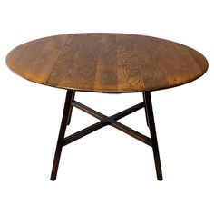 a wooden table with two crossed legs and a round shaped dining table in the middle