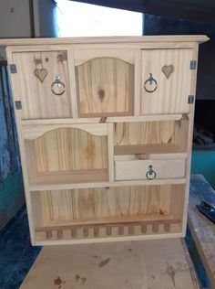 an unfinished wooden cabinet with knobs and handles