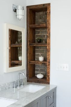 a bathroom with two sinks and an open bookcase on the wall above it is also a mirror