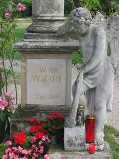 an angel statue sitting next to a red fire hydrant in a flower filled garden