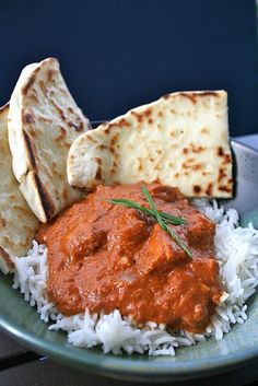 a plate filled with rice, bread and red sauce next to flat bread on the side