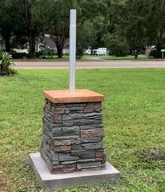 a fire hydrant sitting on top of a stone block in the middle of a field