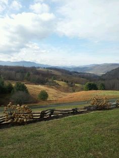 there is a wooden fence in the middle of a field with mountains in the background