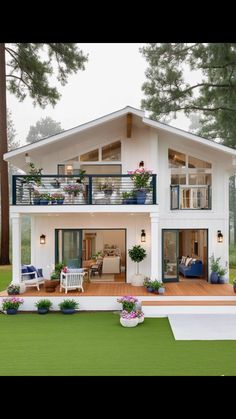 a white house with lots of windows and balconies on the top floor is surrounded by greenery