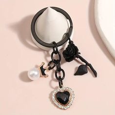 a black and white heart shaped keychain hanging from a ring on a pink surface