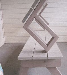 a white bench sitting on top of a cement floor next to a wall and door