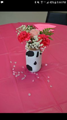 a vase filled with flowers sitting on top of a pink table