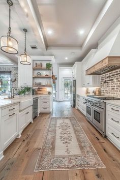 a large kitchen with white cabinets and wood flooring, along with an area rug