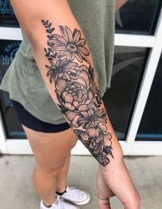 a woman's arm with flowers on it and a hand holding the wrist tattoo