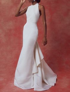 a woman in a white dress posing for the camera with her hand on her head