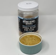 a jar of porridge next to a bowl of grated ground beans on a white surface