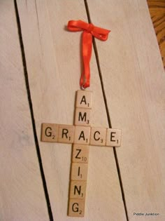 a cross made out of scrabble tiles with an orange ribbon on it that says grace