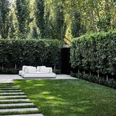 a white couch sitting in the middle of a lush green yard with steps leading up to it