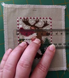 someone's hand is holding up a piece of fabric with a reindeer on it