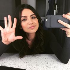 a woman sitting at a table taking a selfie with her cell phone in front of her