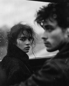 black and white photograph of two people in a car looking out the window at something