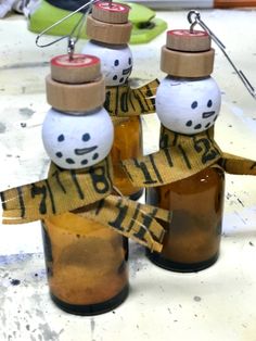 three bottles with snowmen wrapped in yellow tape and some scissors are on the table