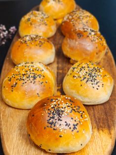 bread rolls with sesame seeds are arranged on a wooden platter, ready to be eaten