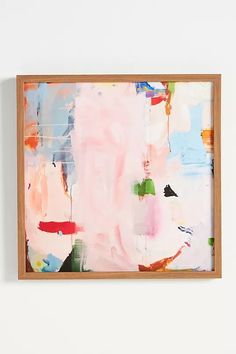 an abstract painting hanging on the wall next to a white wall with a wooden frame