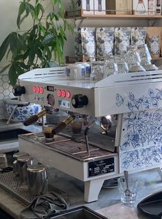 an espresso machine sitting on top of a counter next to a potted plant