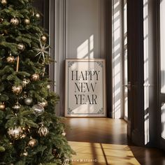 a happy new year framed sign next to a christmas tree in a room with sunlight streaming through the windows