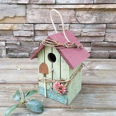 a birdhouse with a pink roof on a wooden table