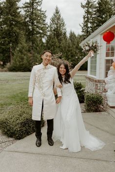 a man and woman standing next to each other in front of a house holding hands